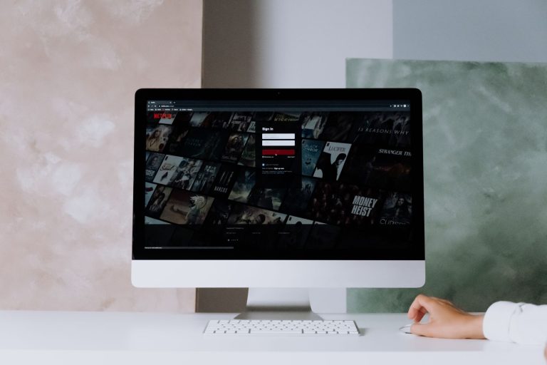 Tela de computador exibindo uma interface de serviço de streaming em um ambiente de escritório moderno