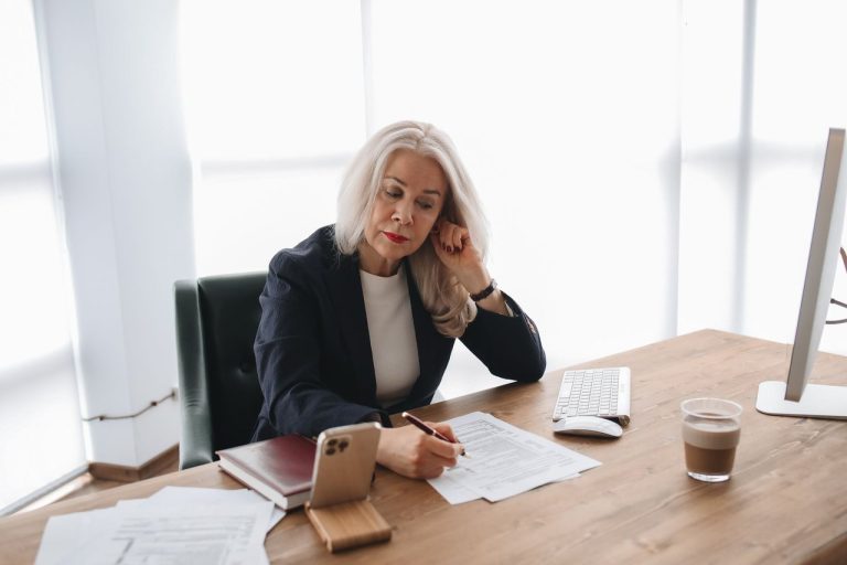 Antes de 2027, empresas do Simples terão de transformar prazos fiscais em plano de ação Empreendedora analisa documentos em uma mesa de escritório, ao lado de um celular e um computador.