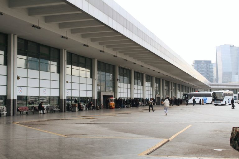 Terminal rodoviário movimentado, com passageiros e ônibus estacionados.